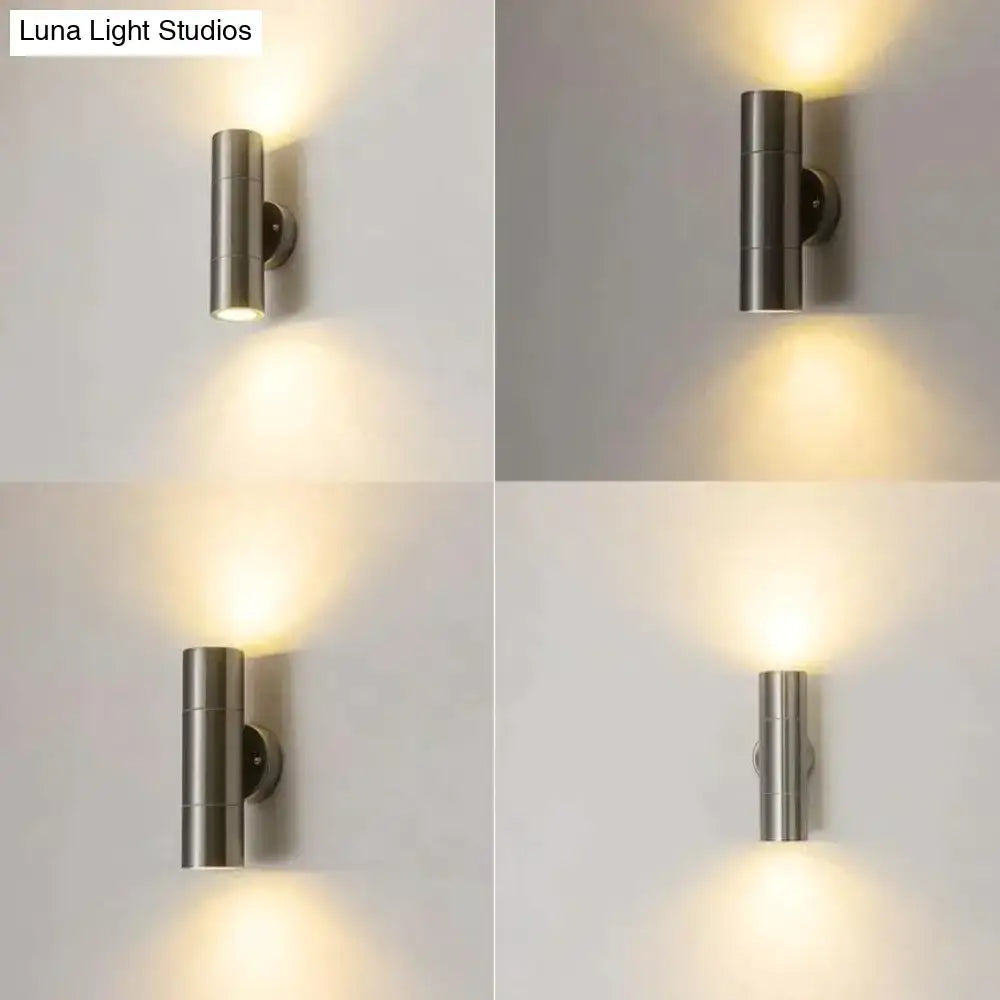 Modern silver cylindrical wall sconce in brushed stainless steel with dual downward-facing lights for outdoor use