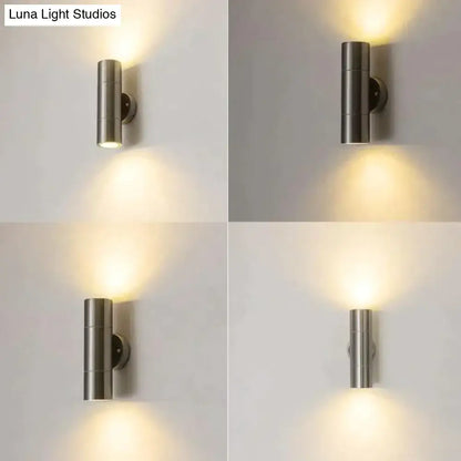 Modern silver cylindrical wall sconce in brushed stainless steel with dual downward-facing lights for outdoor use