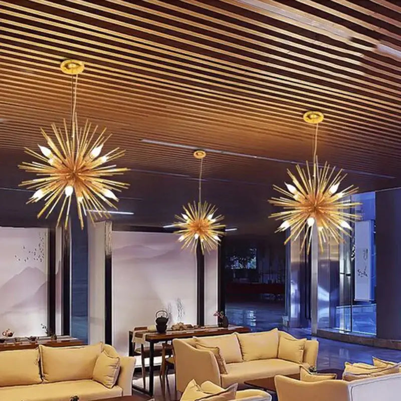 Three golden dandelion sea urchin pendant lights with slender arms hanging from a wooden slat ceiling decorbites dandelion sea