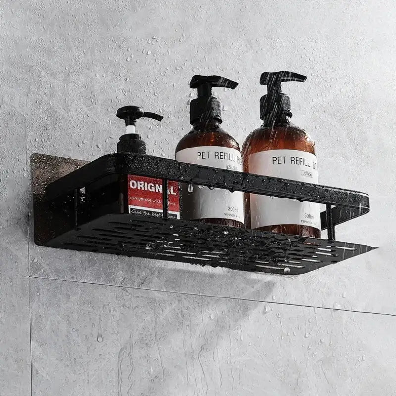 Modern silver double tiered decorbites corner shower shelf with black metal perforated caddy holding amber pump bottles