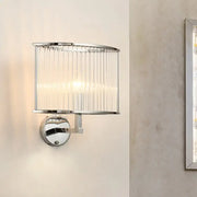 Modern wall lamp with silver finish and clear crystal cylindrical glass shade featuring vertical ridges for living room use