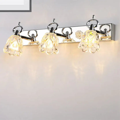 Modern silver finish wall light with clear glass flower-shaped shades emitting warm glow for bathroom use