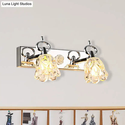 Modern silver finish wall light with clear glass crystal flower-shaped shades emitting warm glow for bathroom use