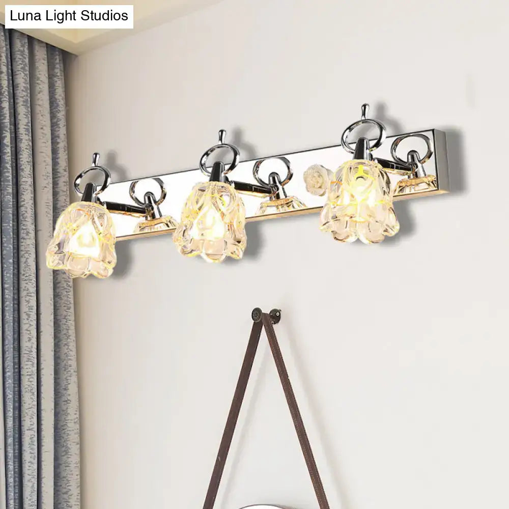 Modern silver finish wall light with clear glass crystal flower shades emitting warm glow for bathroom vanity