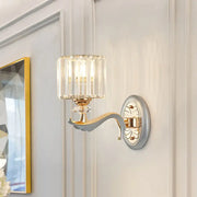 Elegant flush mount wall light with gold-toned metal arm, clear crystal shade, and vertical faceted glass panels refracting light