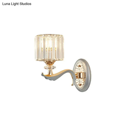 Elegant modern silver flush mount wall light with clear crystal shade and gold-toned metal arm on ornate silver backplate