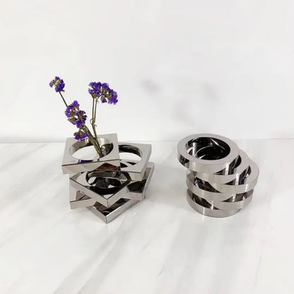 Modern silver geometric circle crystal glass vase with interlocking rings holding dried purple flowers for living room decor