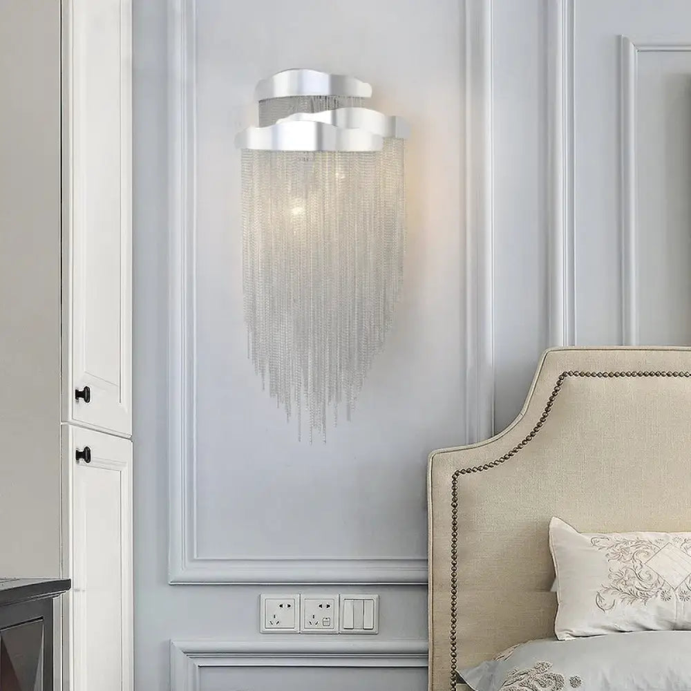 Modern silver wall lamp with tassel design and bulb base featuring cloud shape and cascading crystal chains for bedroom