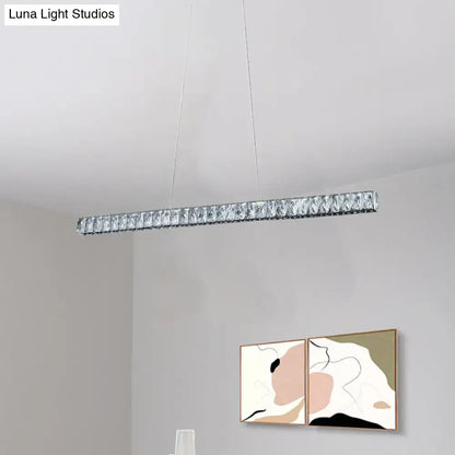 A sleek silvery linear crystal block island pendant light with clear facets for modern dining room suspension