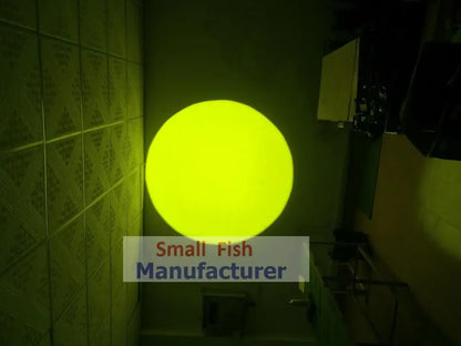 A glowing yellow spherical light fixture of a modern silver metal 300w led follow spot light mounted on a tiled wall