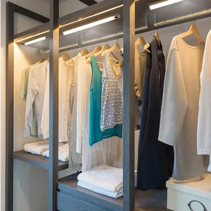 Modern silver rectangular led cabinet light with hand sweep switch illuminating a gray wood-framed walk-in closet