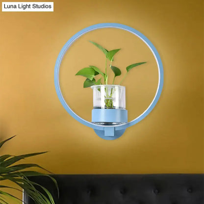 Modern silver wall light with light blue circular plant pot and clear glass vase holding green leaves 110v-120v