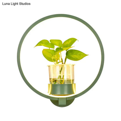 Modern silver wall light 110v-120v with green circular plant pot and clear glass vase holding vibrant green leaves