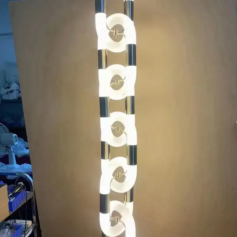 A modern silver and white tall floor lamp with sleek chrome frame and crystal gold chain chandelier light fixtures