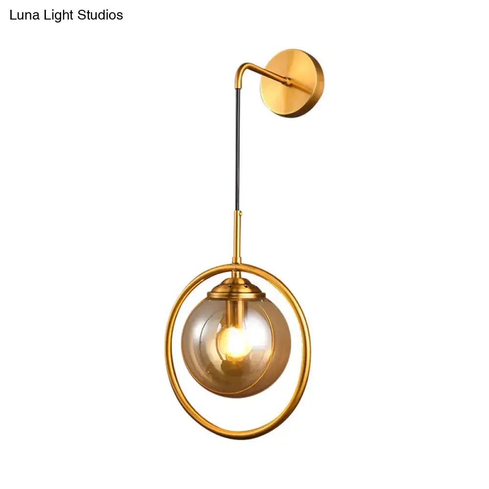 Modern smoke gray clear glass globe sconce with gold-toned circular frame and amber glass globe for bedroom wall lighting in 220v-240v 110v-120v