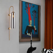 A modern smoke gray glass wall light with brushed silver cylindrical shade and gold-toned arms for living room use