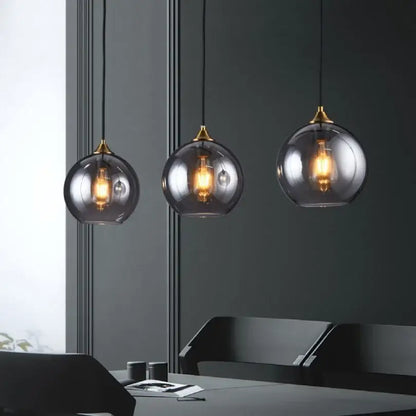 Modern smoked glass ball pendant lights with brass accents and exposed bulbs for kitchen and dining decorbites glass ball