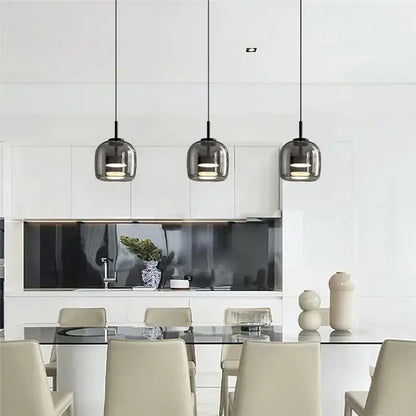 Three sleek dark gray smoked glass bowl chandelier pendant lights with black cords above a modern dining table