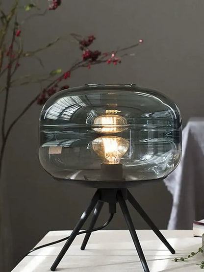 Modern smoked glass desk lamp with a translucent gray glass shade and tripod base for decorbites glass desk use