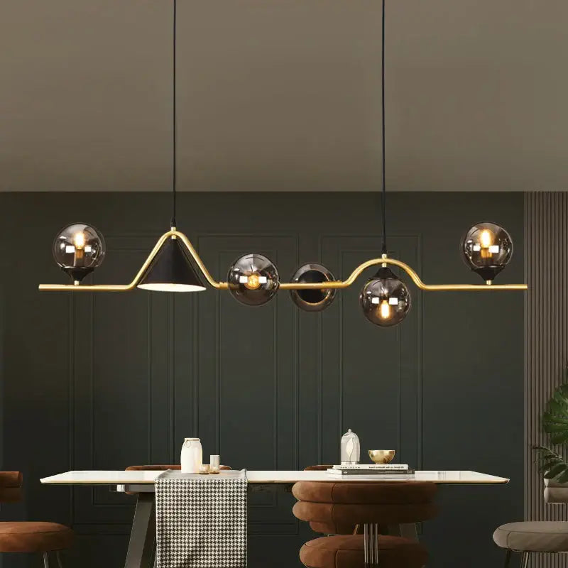 Modern gold-toned pendant light with a sleek curved frame and five smoky grey glass globe shades for dining rooms