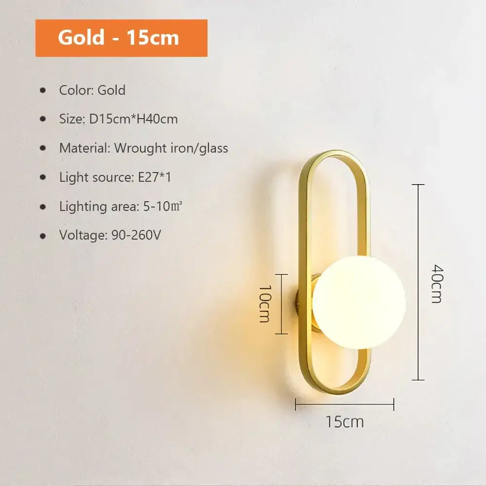 Gold-colored wall lamp with sleek elongated oval frame and round spherical glass shade gold for bedroom use