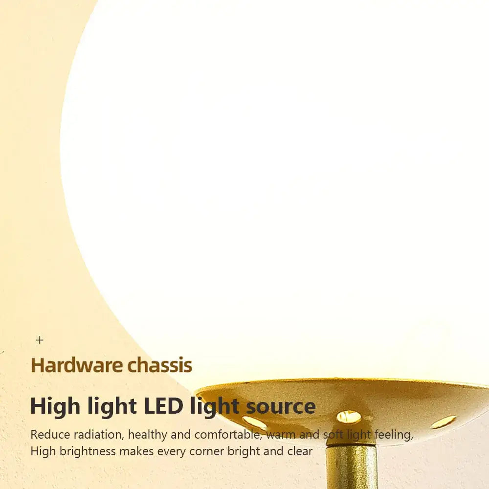 A modern wall lamp with a frosted white spherical glass shade and brushed gold metal base for bedroom use