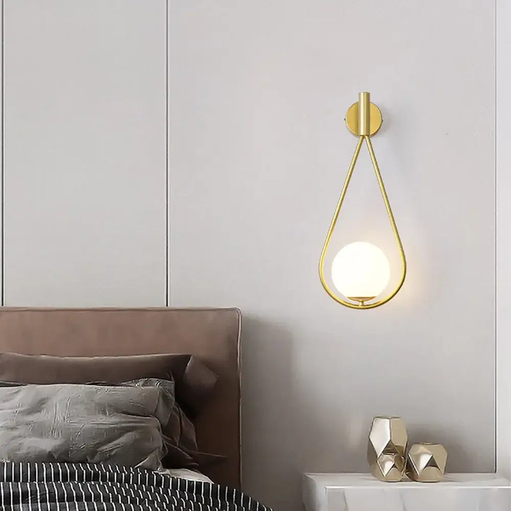 Modern spherical glass shade gold wall lamp with gold-toned teardrop metallic frame and frosted glass shade gold bulb