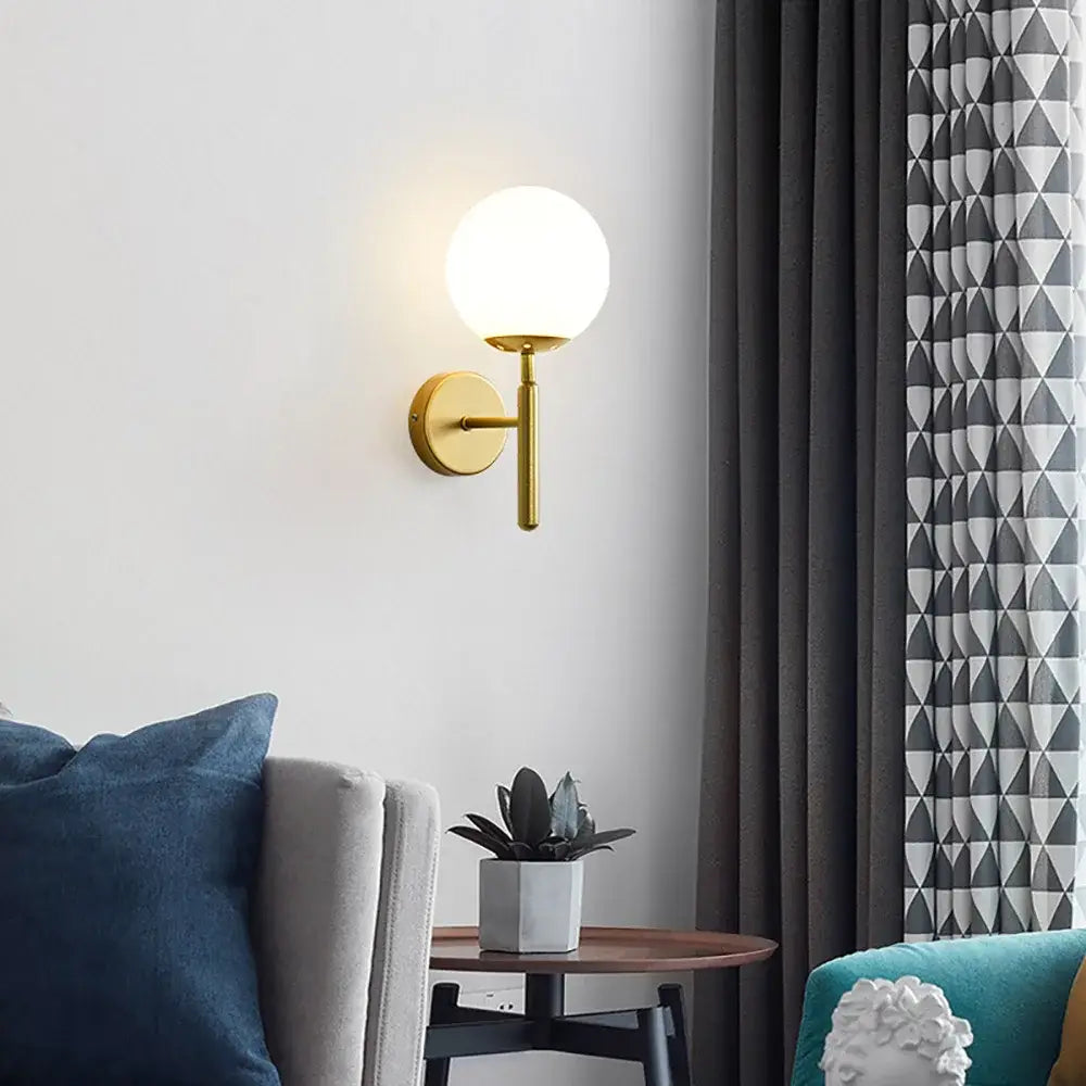 Modern spherical glass shade gold wall lamp featuring a gold-toned wall sconce with a frosted globe shade for bedroom