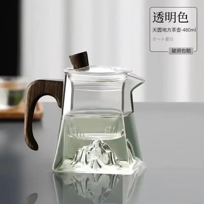 Modern square glass tea pot with dark wood handle and lid featuring an embossed mountain design at its base