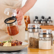 Modern stainless steel and glass seasoning pot with clear glass seasoning container filled with red pepper flakes