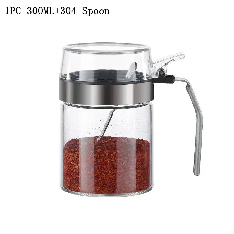 Clear glass seasoning pot with stainless steel lid and handle containing red chili flakes for kitchen supplies
