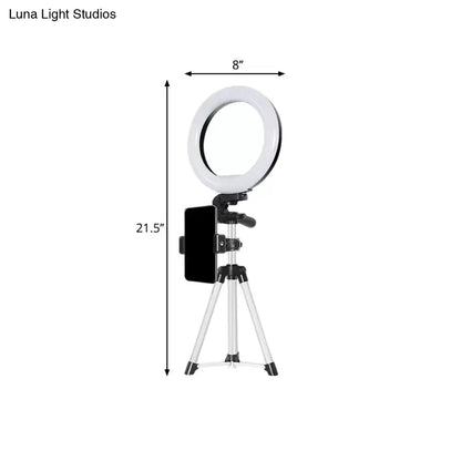 Modern style black and silver led ring flash light with 8-inch white circular light mounted on a tripod with phone clamp