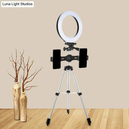 Modern style black and silver led ring flash light with white illuminated band mounted on silver tripod for office use