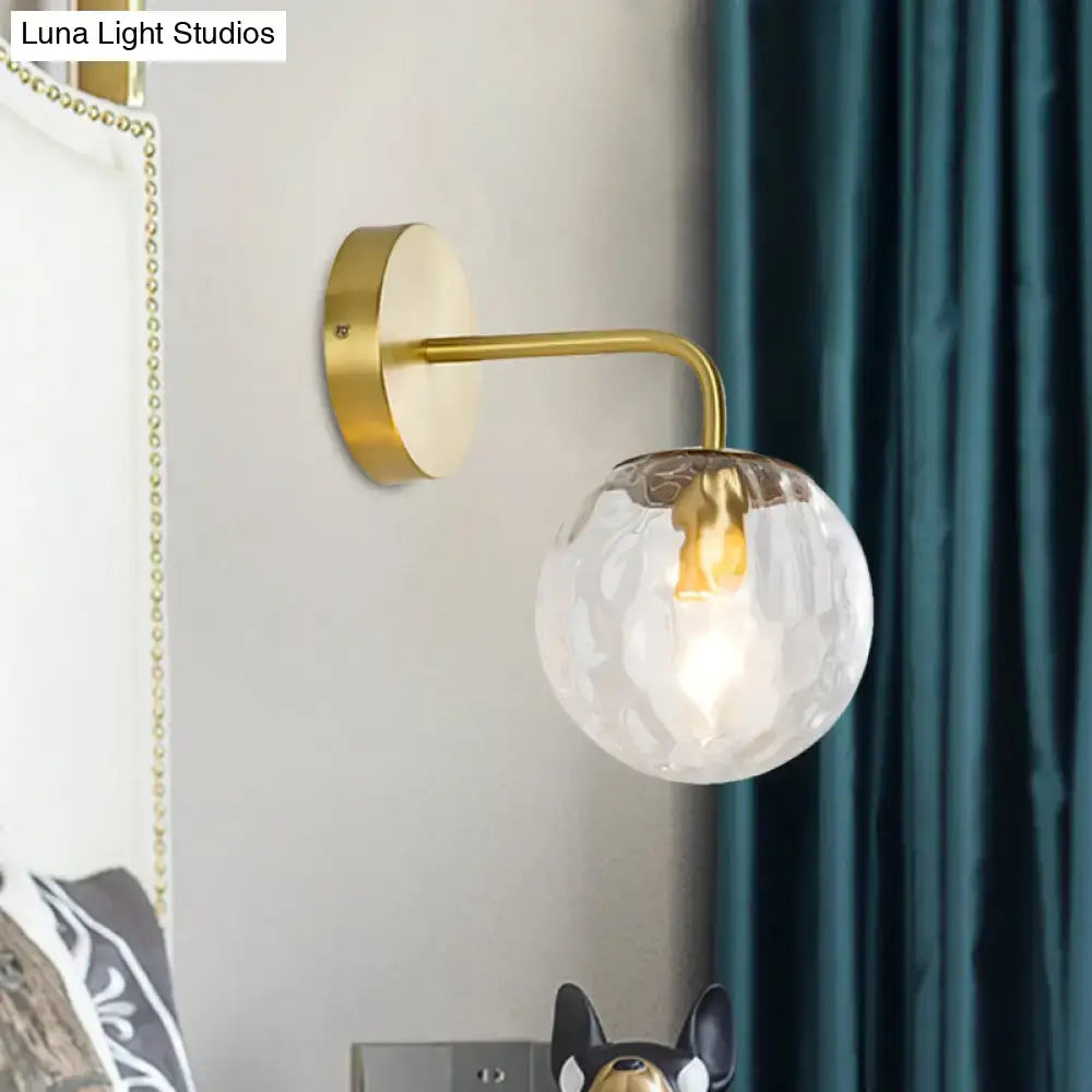 Modern style gold color wall sconce with hammered base and faceted clear glass globe for living room lighting