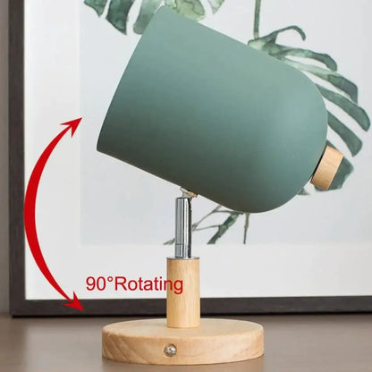 Modern teal and wood wall lamp with a matte sage green cylindrical shade, wooden base, and adjustable metal stem