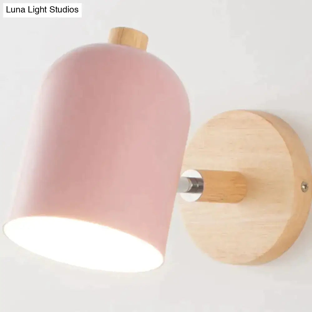 Pink matte-finished cylindrical wall lamp with natural wood base and mounting plate for modern bedroom decor