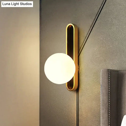 Modern teal and terracotta cylindrical side table paired with a gold orb wall light featuring a frosted glass globe