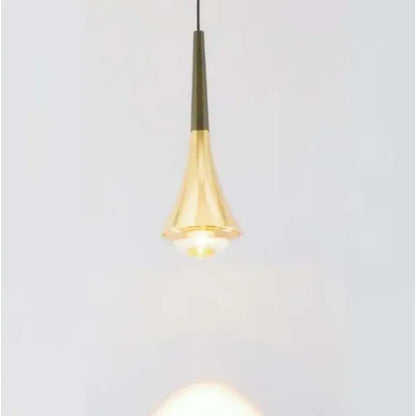 A sleek golden brass conical cord pendant light with a smooth reflective surface for modern dining rooms
