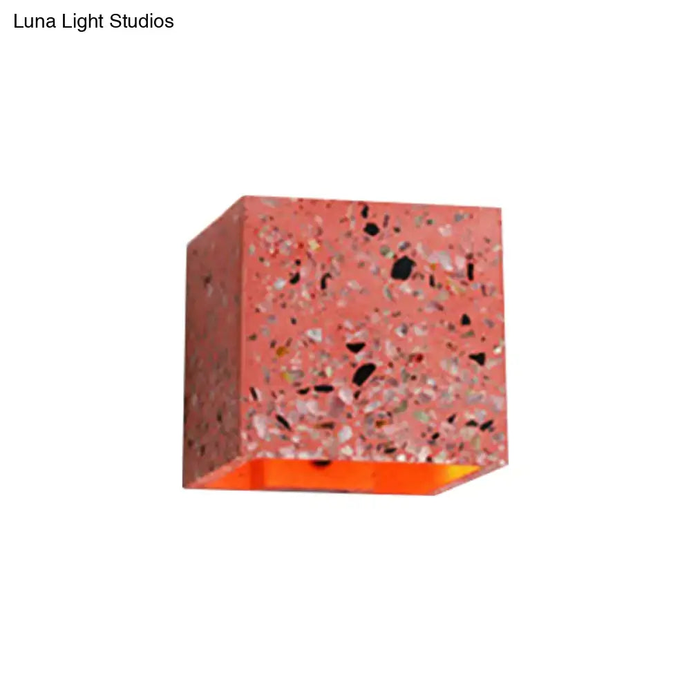 A coral-colored terrazzo cube wall light with glowing orange interior compatible with e26 e27 light bulbs