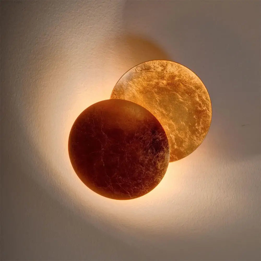 Modern textured eclipse round wall lamp with warm amber and deep orange translucent finish for bedroom use