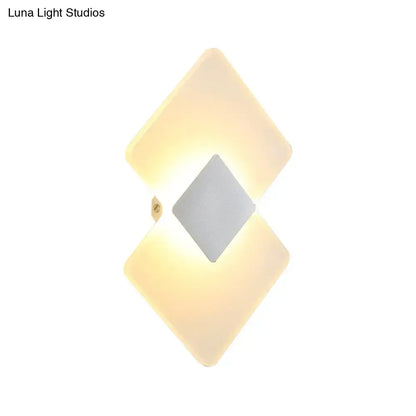 Modern textured silver and black direct wired electric wall sconce with diamond shape and warm glow for bedroom use