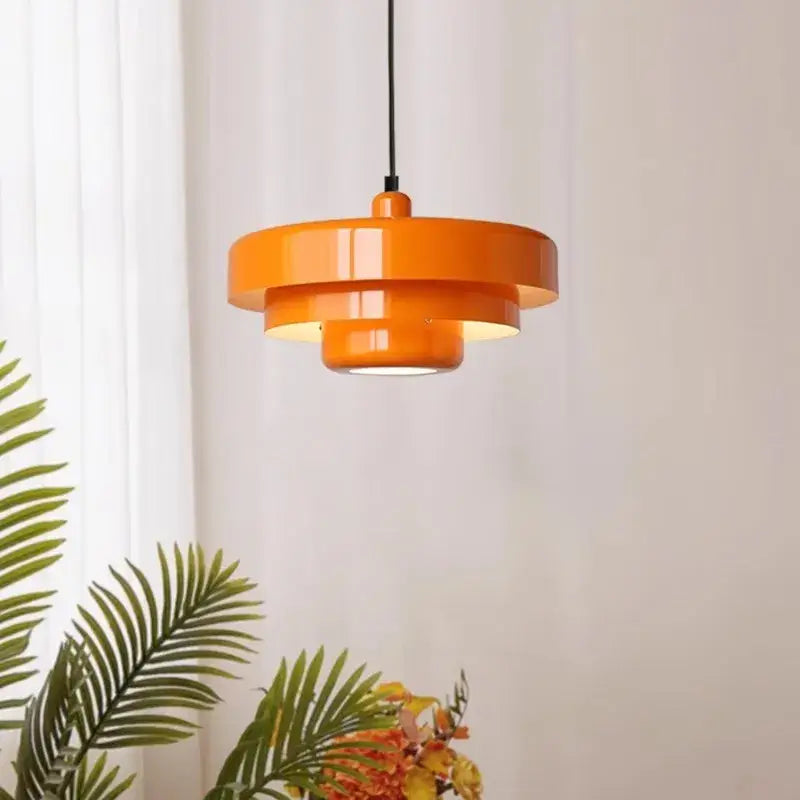 Vibrant orange tiered pendant light with glossy finish and concentric circular design ideal for decorbites dark green settings