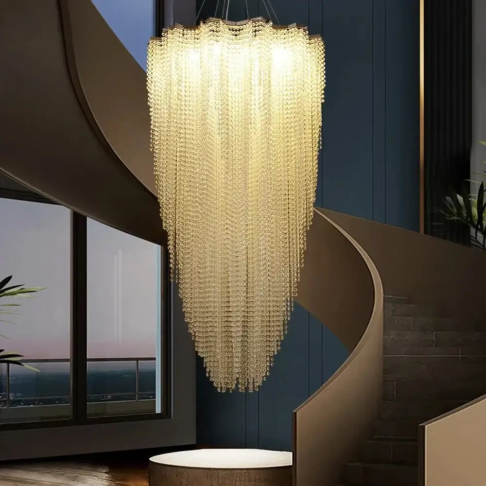 A modern tiered decorbites colorful crystal chandelier in golden tones hanging elegantly above a staircase