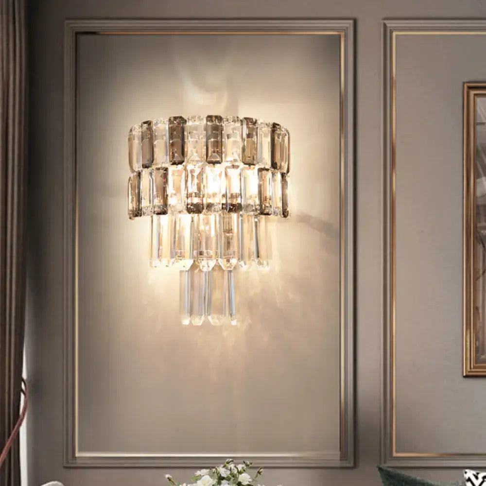 Modern tiered smoke gray crystal wall sconce with clear and smoky glass rods on a sleek metallic frame for living room