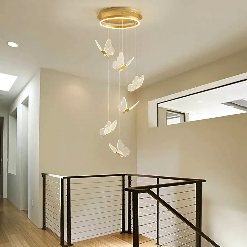 A modern gold-toned circular pendant light with five translucent white butterfly staircase pendant lights for stairwell decorbites decor