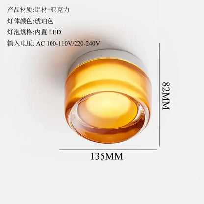 A sleek amber dimple potato chip wall lamp with cylindrical acrylic body and aluminum top featuring integrated led bulb