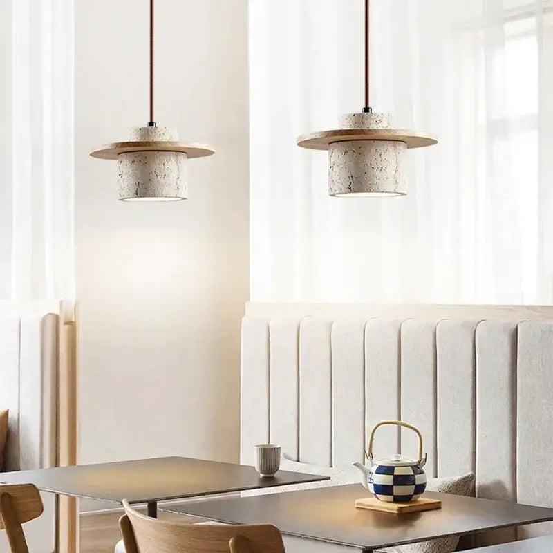 Two modern travertine and walnut pendant lights with textured concrete bodies and cord pendant led bulbs for kitchens