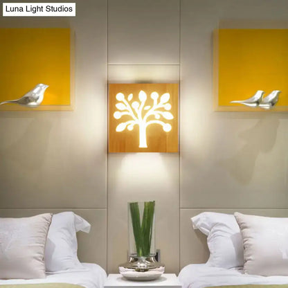 A warm illuminated wooden square flush mount wall sconce with a stylized tree design for corridor lighting