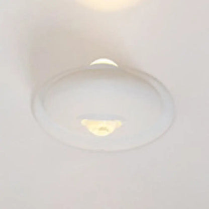 A sleek white and chrome modern triangle bedroom wall sconce lamp with a smooth rounded dome led bedroom wall light