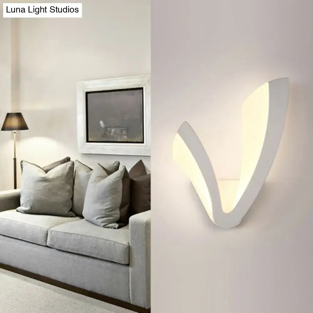 Modern white v-shaped wall mounted light with a sleek minimalist design providing warm white ambient bedroom lighting